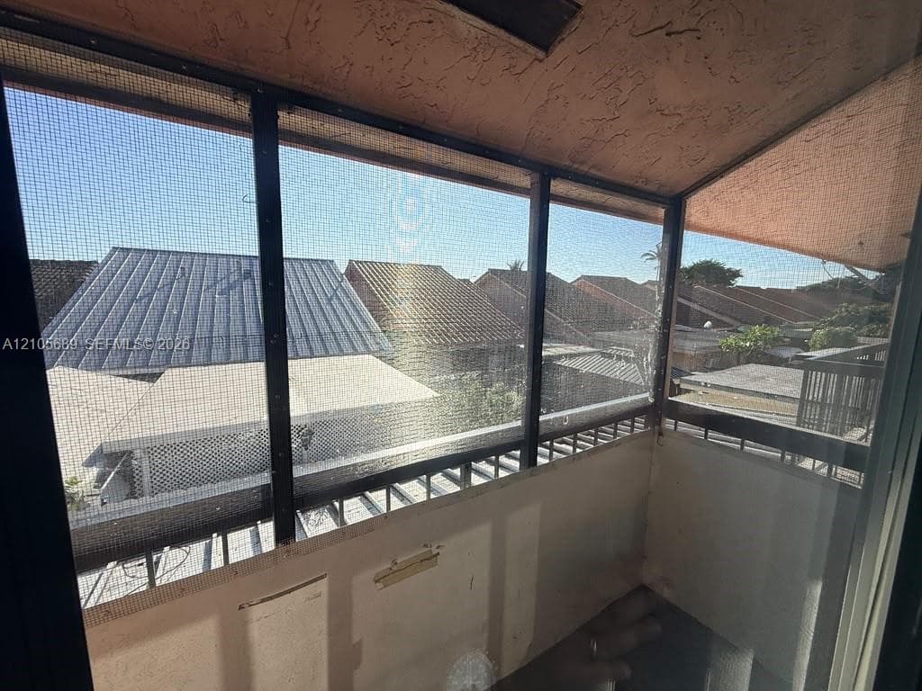 Screened-in balcony featuring a solid ceiling structure and a metal railing