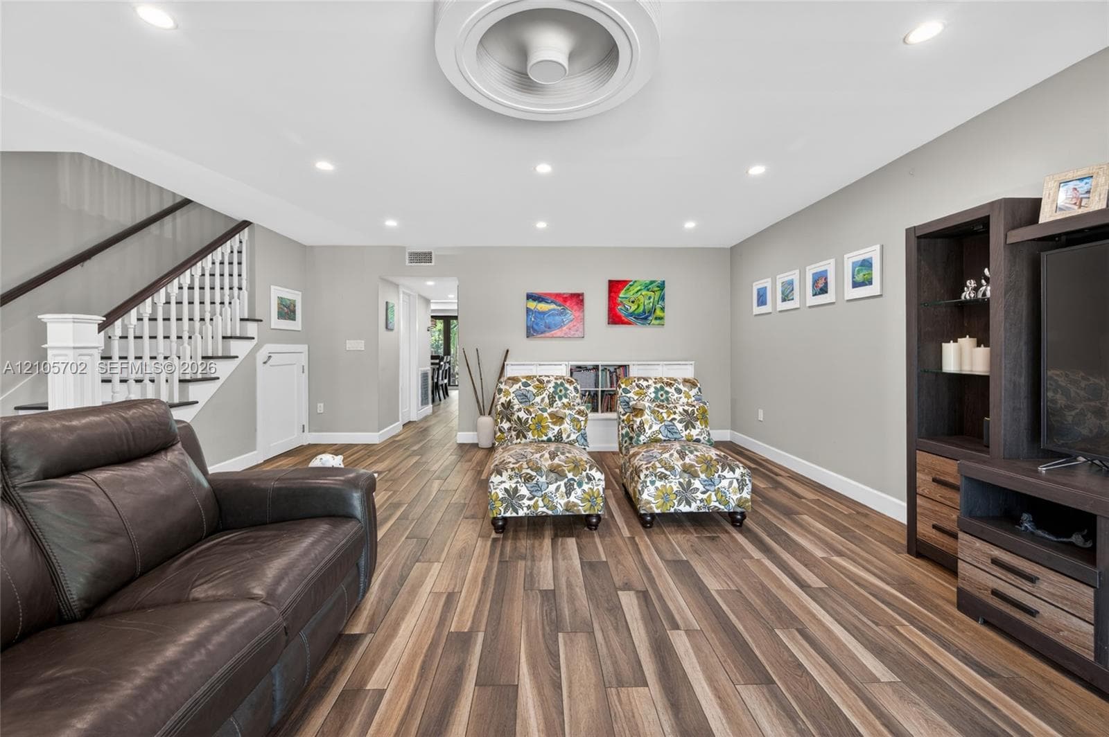 Interior space featuring wood-finish flooring, recessed lighting, a circular ceiling detail, and a wooden staircase with white balusters