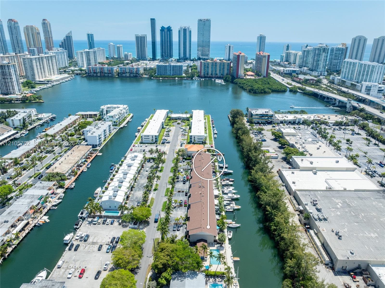 Aerial perspective featuring a waterfront building with dedicated boat slips, direct waterway access, and a surface parking lot