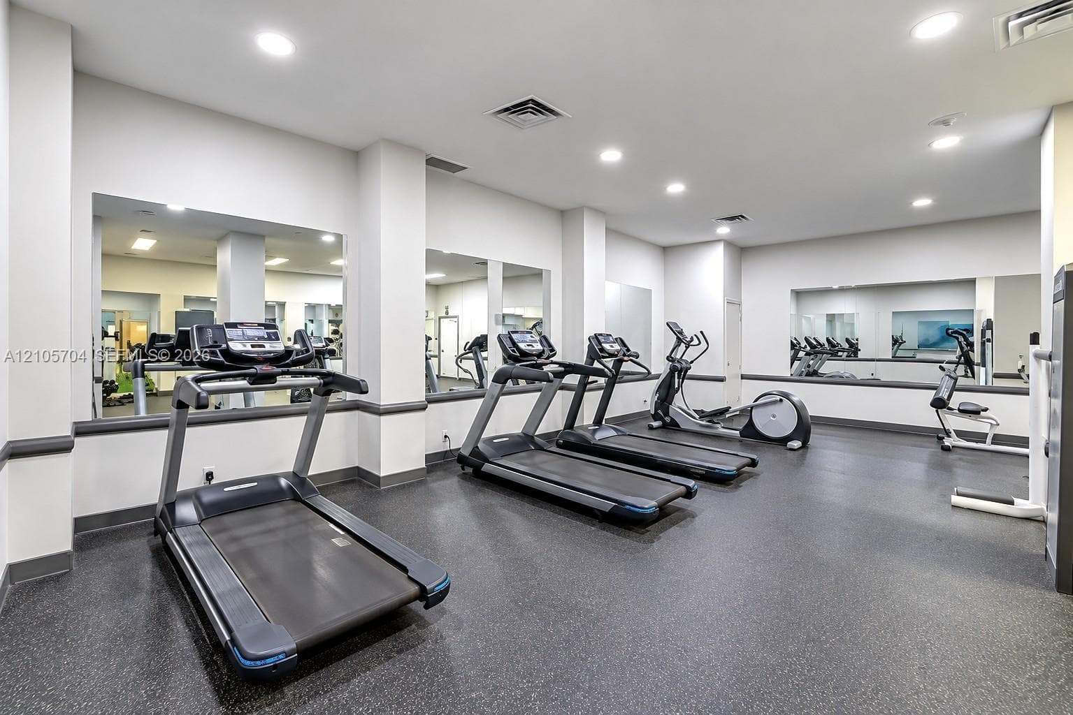 Fitness center featuring wall-to-wall mirrors, recessed lighting, and durable rubber flooring