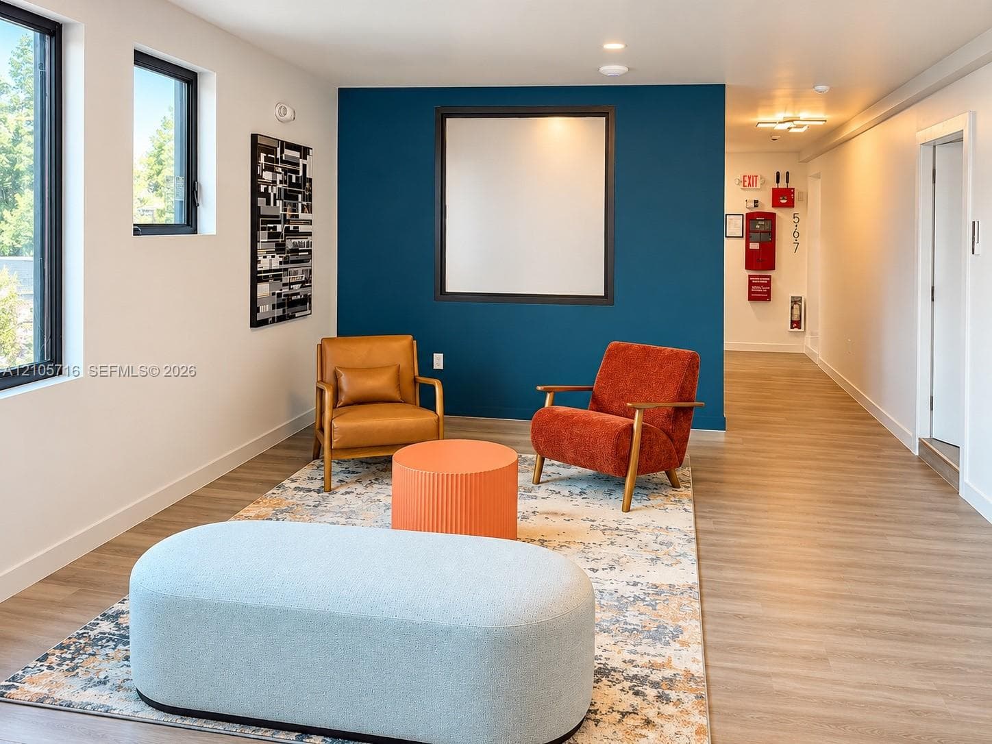 Wood-finish flooring, accent wall, and large windows with black frames
