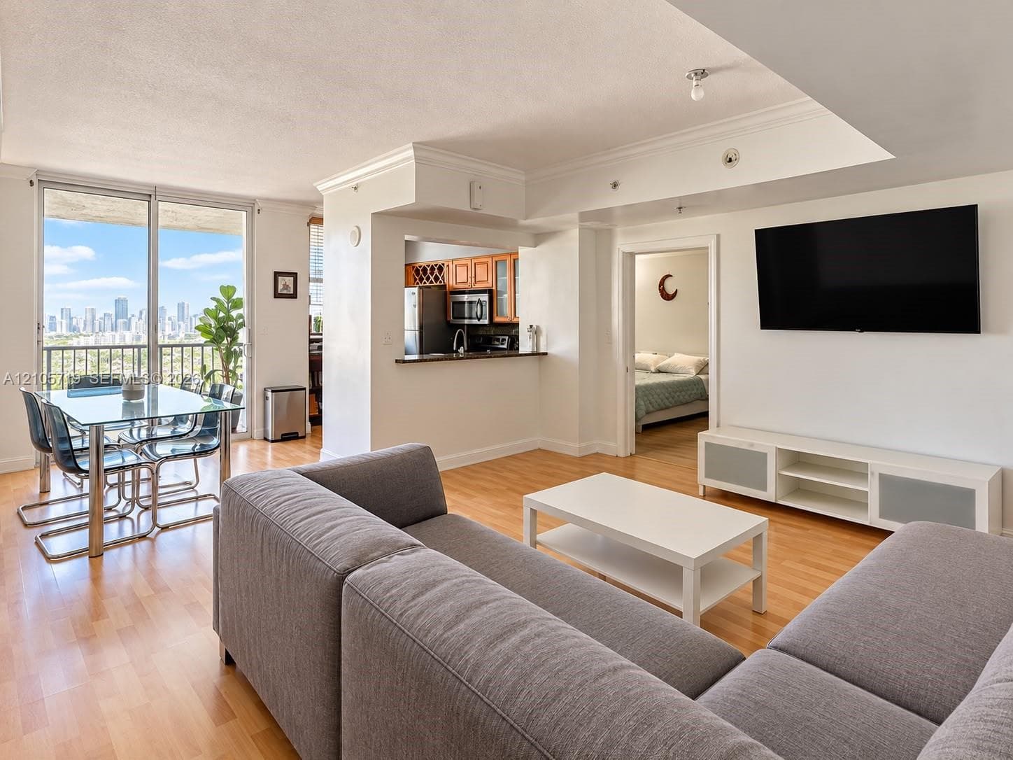 Open-concept floor plan featuring wood-finish flooring, floor-to-ceiling glass sliding doors, built-in cabinetry, and crown molding