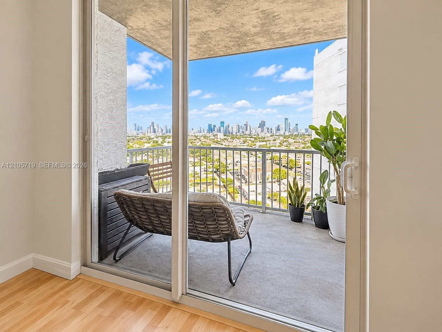 Private balcony featuring concrete flooring, a metal railing, and a cityscape backdrop, accessible through glass sliding doors