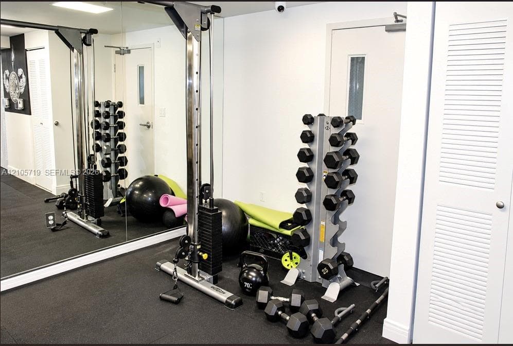 Fitness space featuring floor-to-ceiling wall mirrors, durable rubberized flooring, and dual white louvered-panel doors