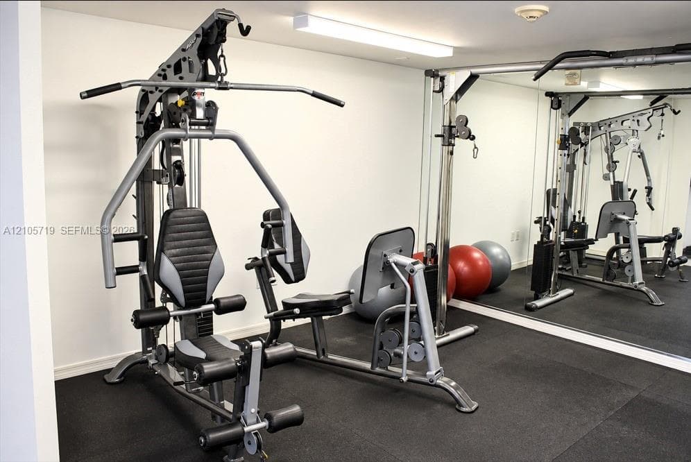 Fitness area featuring wall-to-wall mirrors, industrial-grade rubber flooring, and overhead LED strip lighting