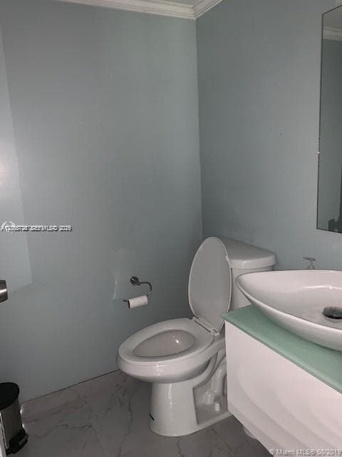 Wall-mounted vanity with a frosted glass countertop and white vessel sink, paired with a white two-piece toilet and large-format tile flooring