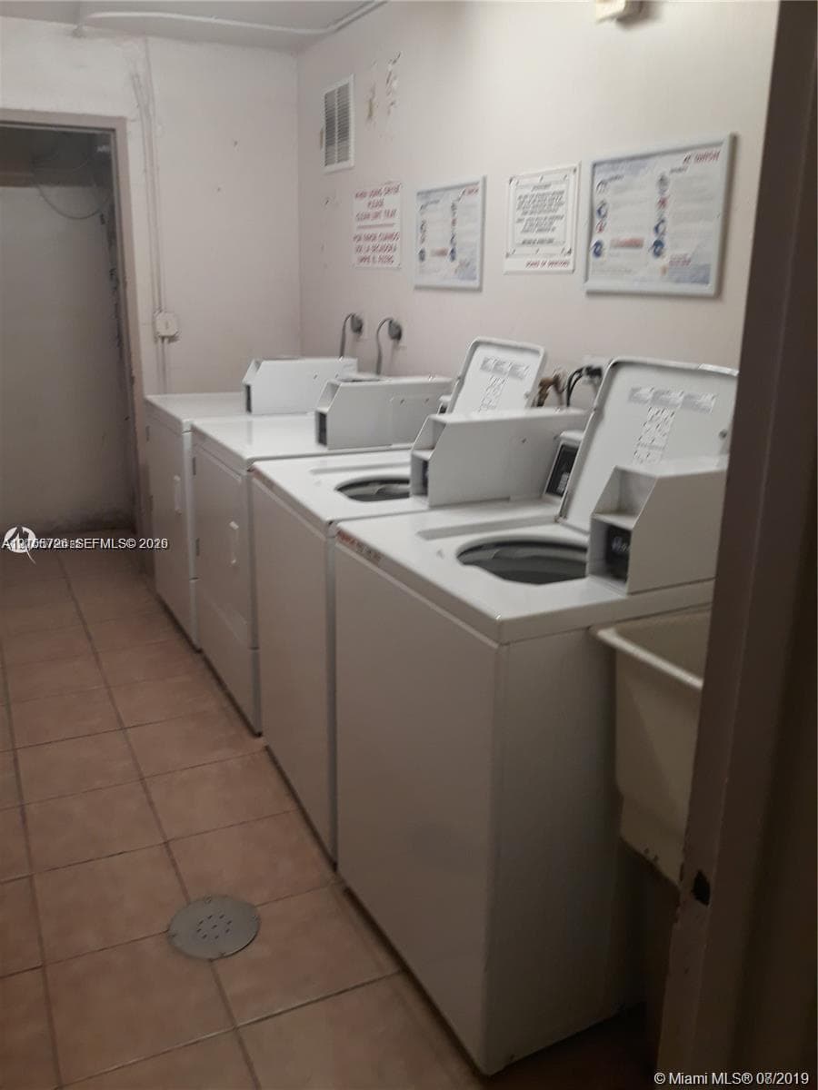 Laundry area featuring multiple top-loading washing machines and ceramic tile flooring