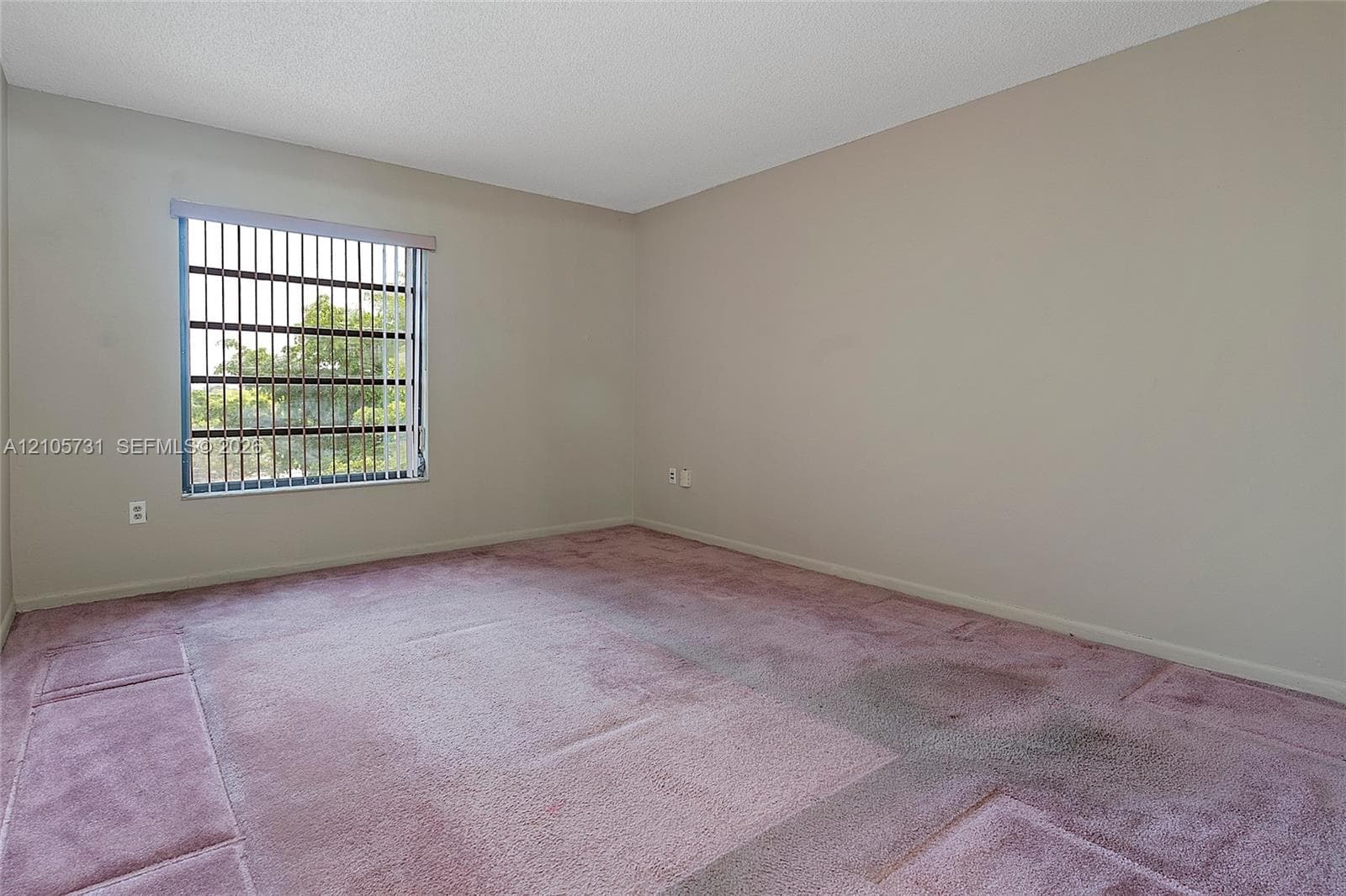 Neutral wall finishes, textured ceiling, vertical window blinds, and wall-to-wall carpeting