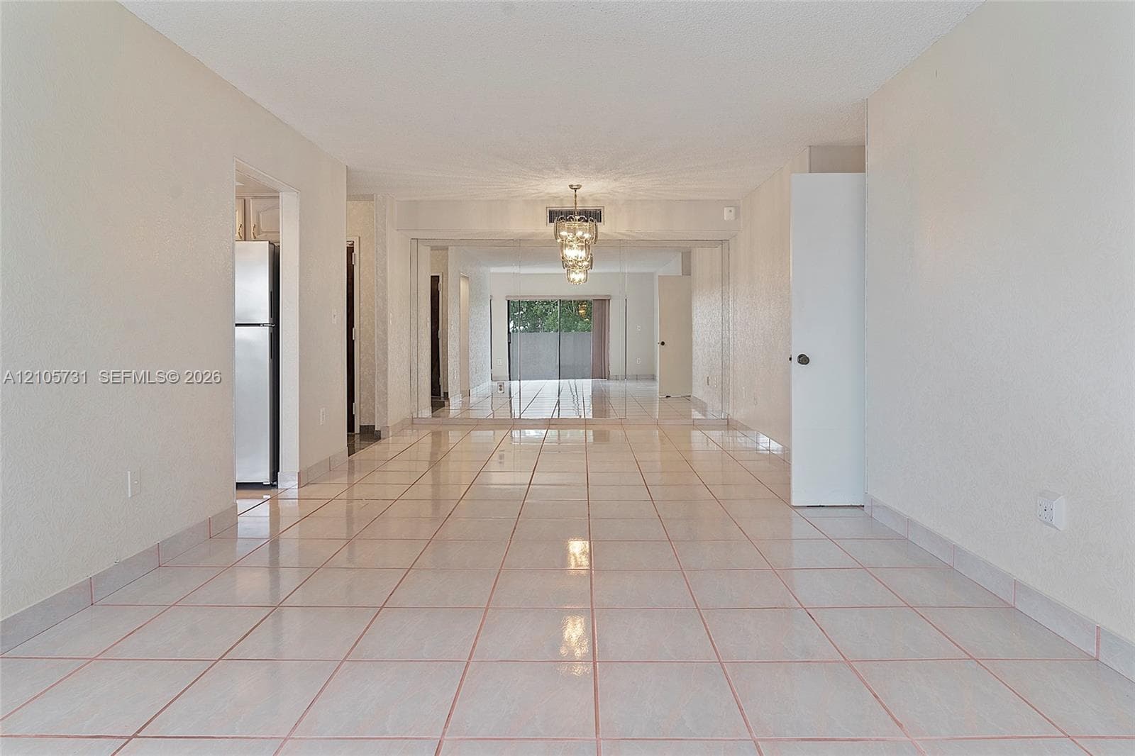 Neutral tile flooring, expansive mirrored wall panels, and a tiered crystal chandelier