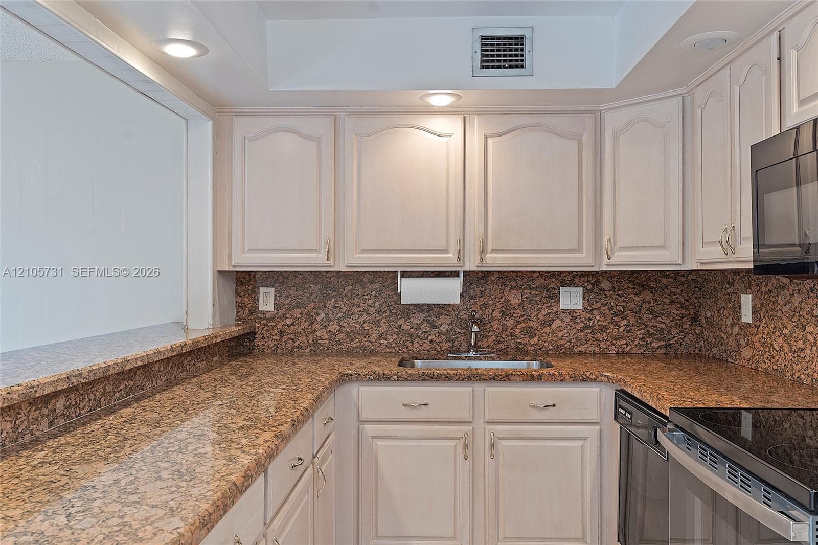 Kitchen featuring stone countertops, stone tile backsplash, light-finish cabinetry, built-in black microwave, and recessed lighting
