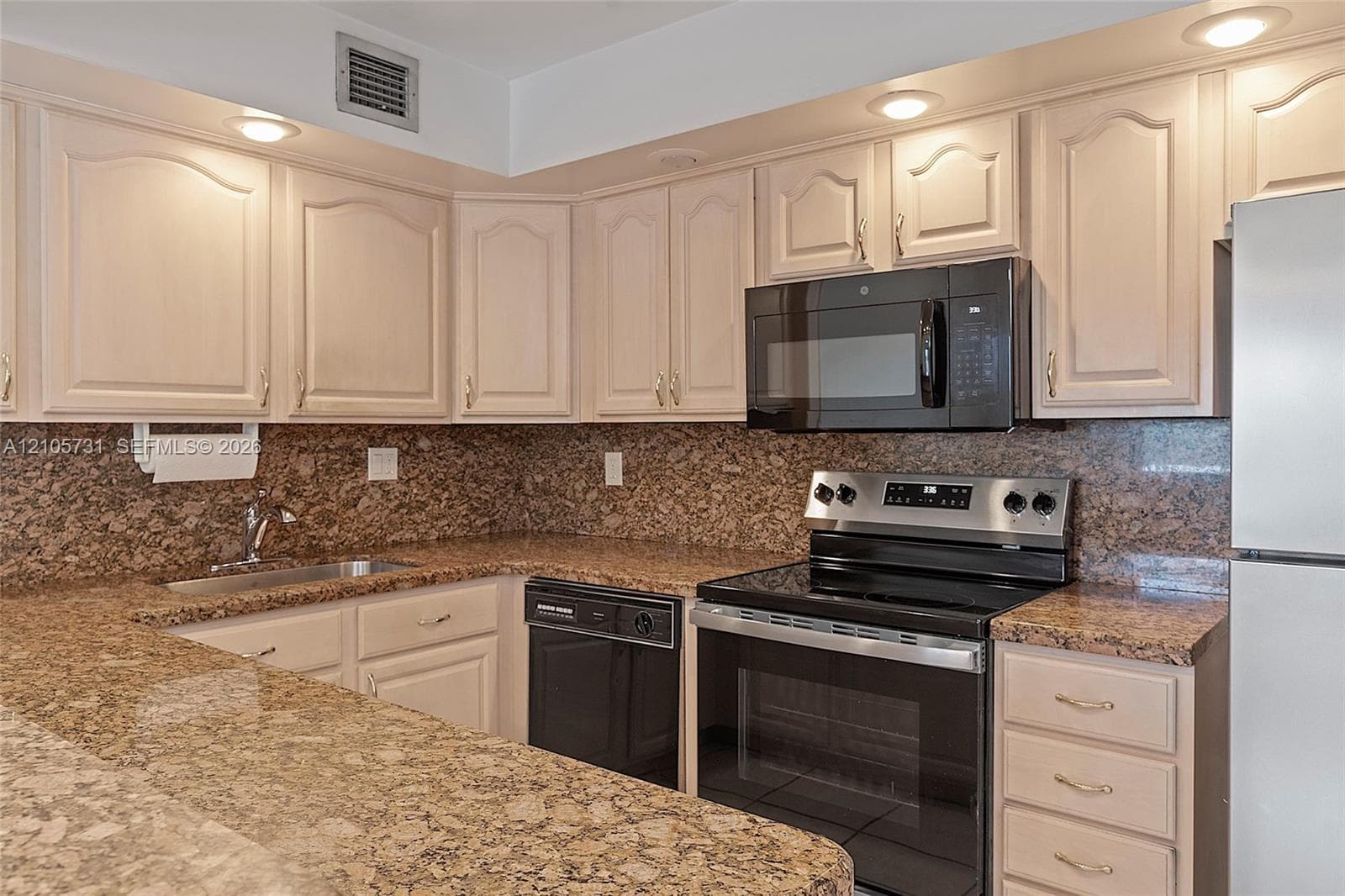 Kitchen featuring neutral-toned cabinetry, stone countertops, stone backsplash, stainless steel appliances, and recessed lighting