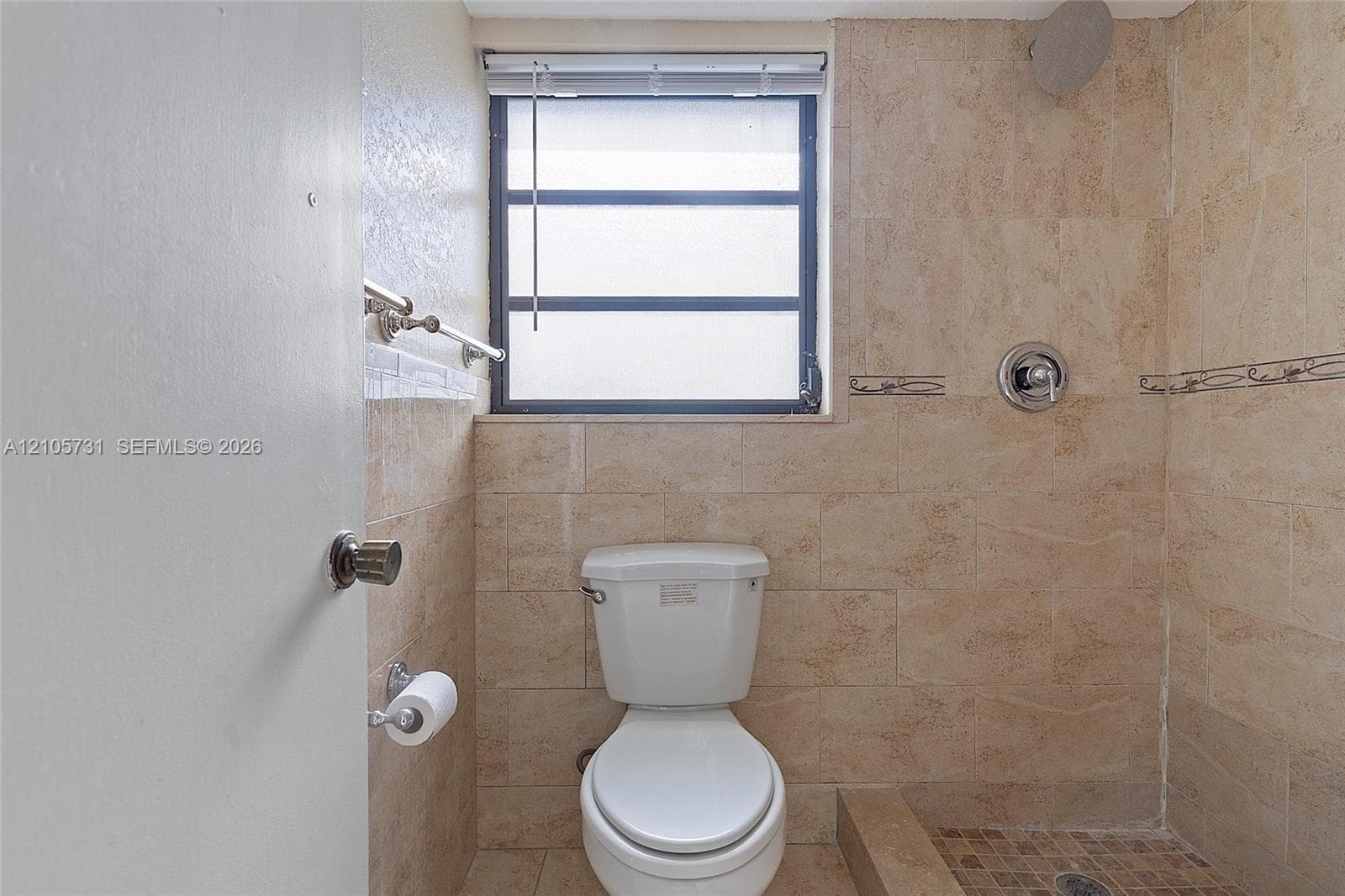 Bathroom featuring full-height neutral stone-finish tile wall surround, stone-tiled shower floor, recessed window with a shutter, chrome plumbing fixtures, and a wall-mounted metal towel bar