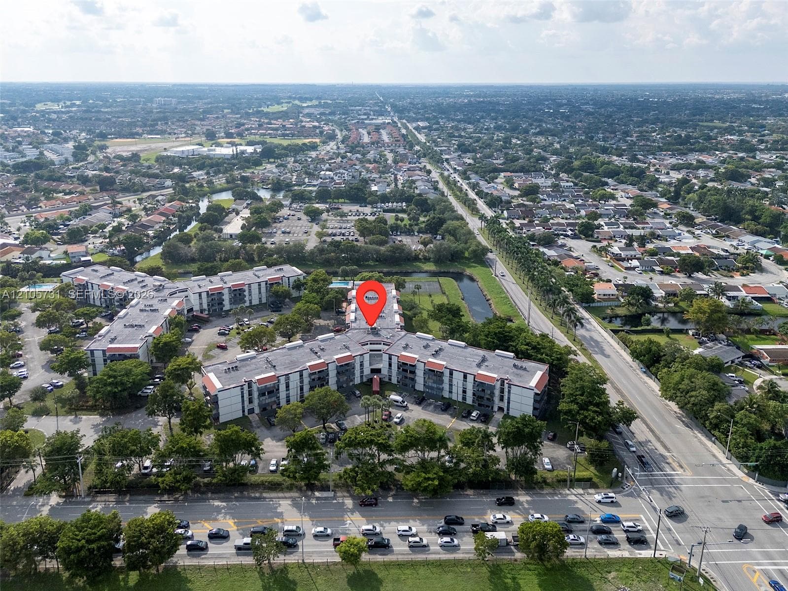 Aerial view of a modern multi-unit residential complex featuring a distinctive curved architectural design with white exterior facades