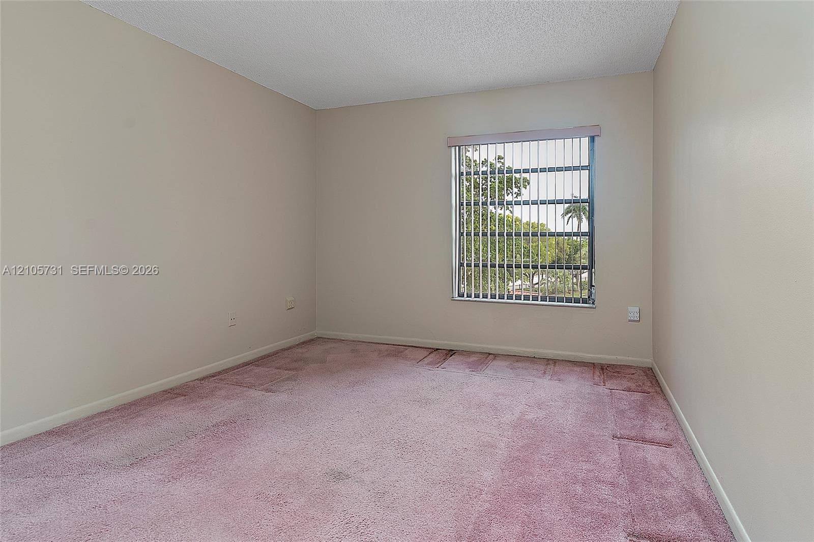 Interior room featuring neutral wall paint, wall-to-wall carpeting, and a window with vertical blinds