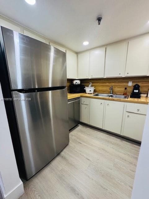 Kitchen featuring stainless steel appliances, wood-finish countertops, shaker-style cabinetry, a dual-basin stainless steel sink with a goose-neck faucet, and wood-finish flooring