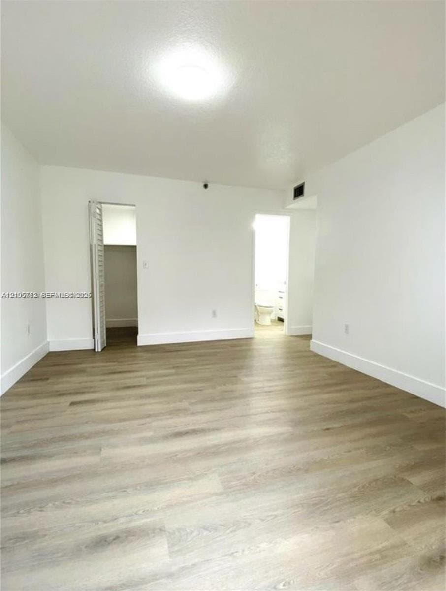 Interior space featuring wood-finish flooring, white walls, and a recessed closet with bi-fold doors