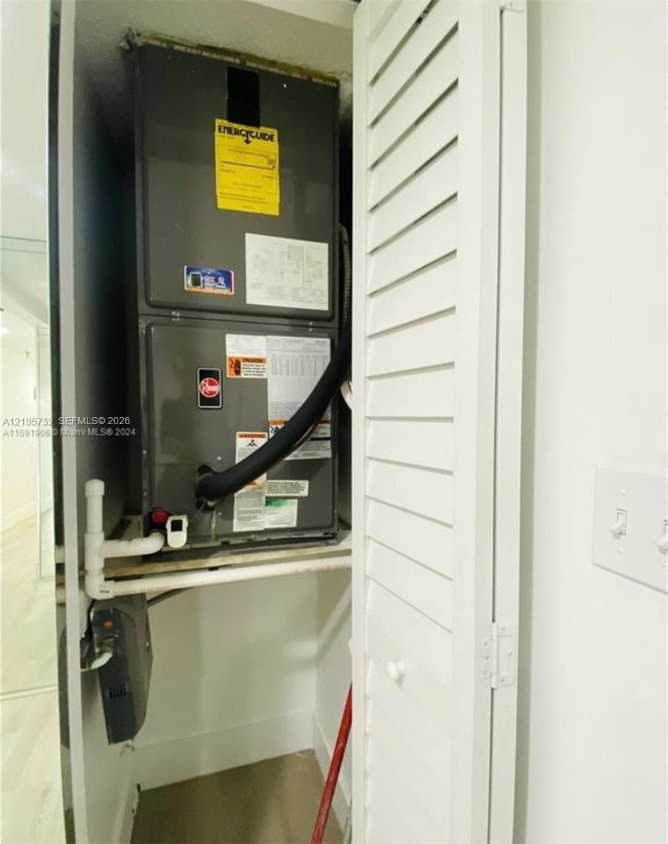 Dedicated utility closet featuring an air handler unit and louvered folding access door