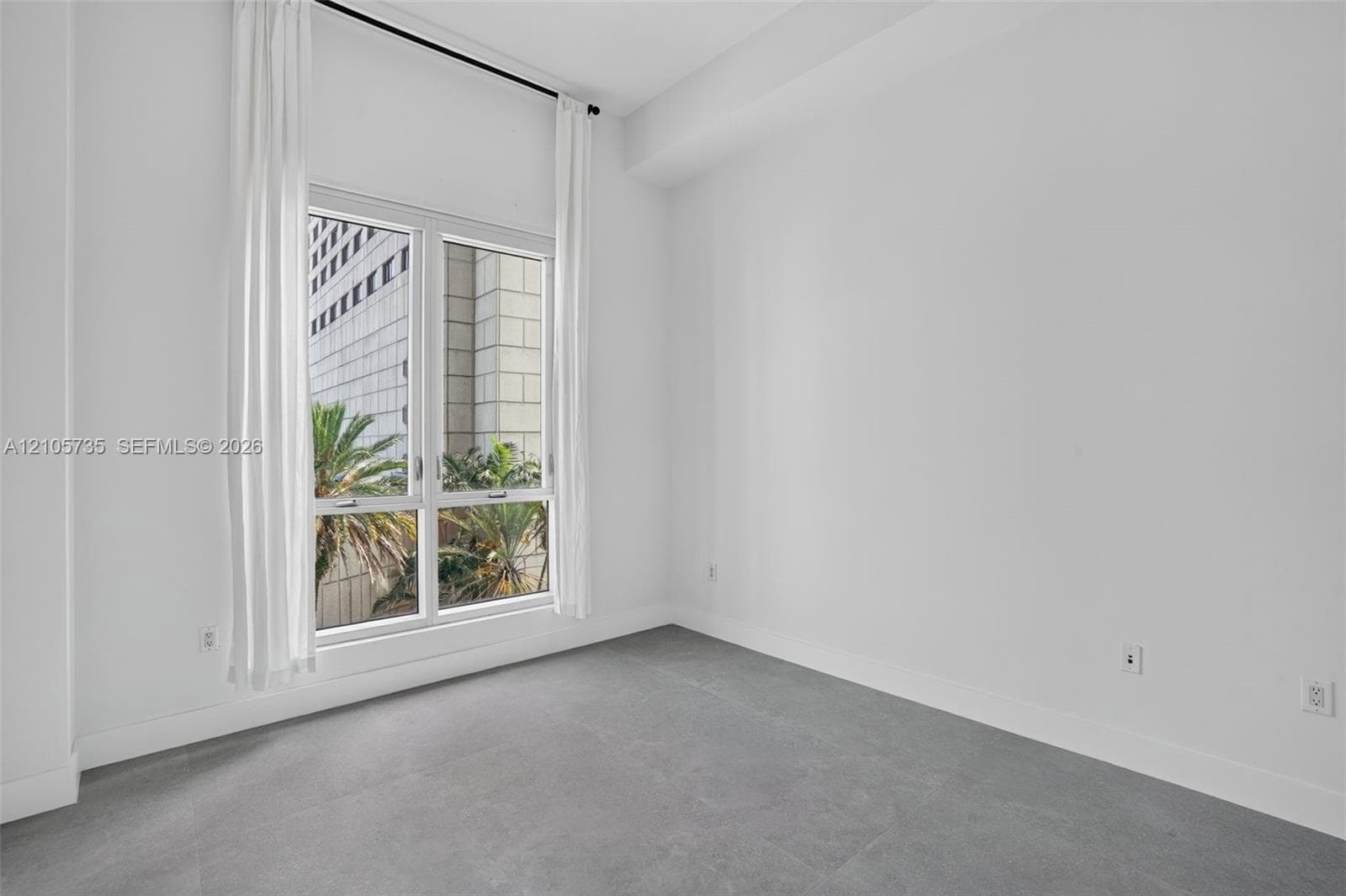 High ceilings featuring a large window with neutral finishes and grey flooring