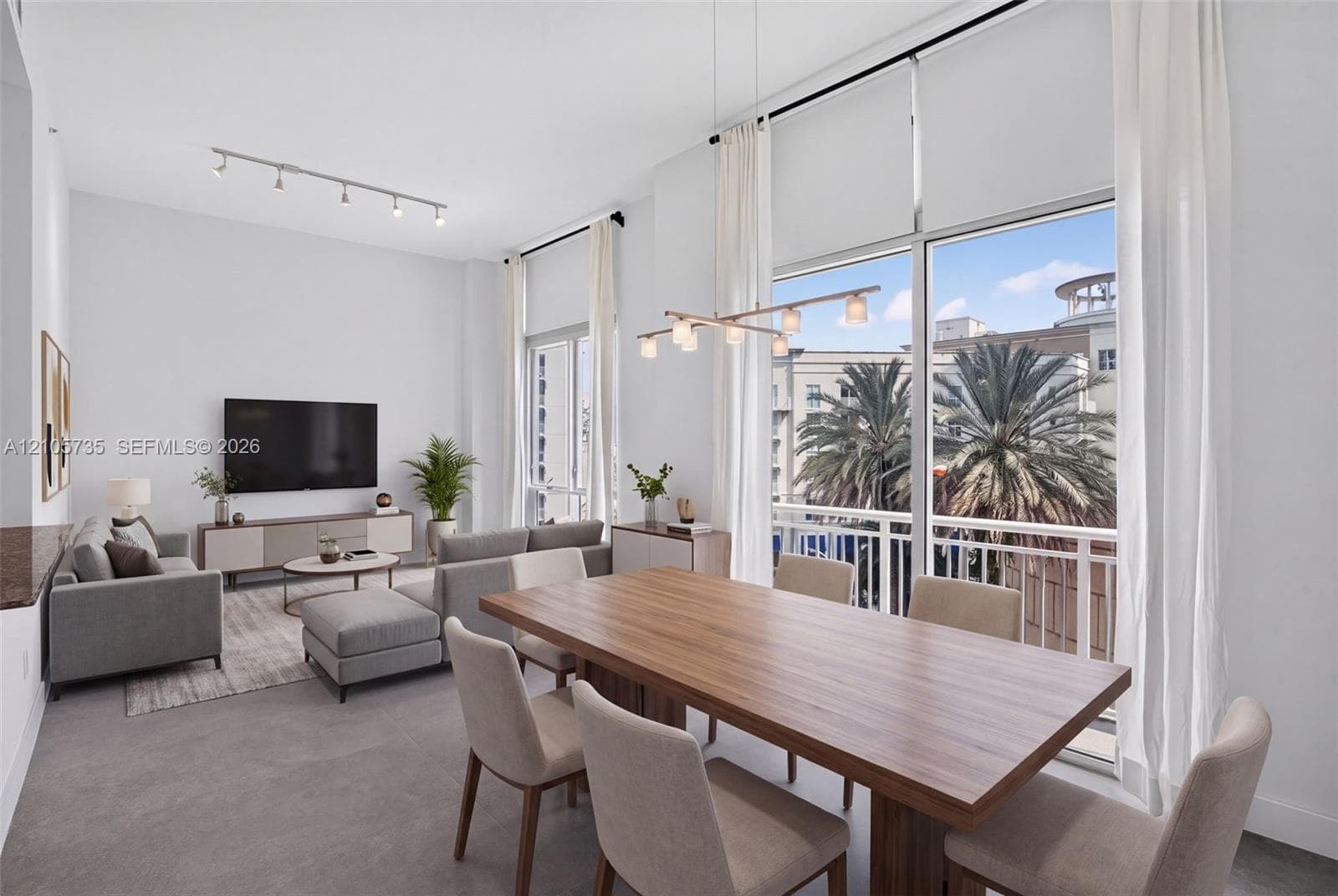 Double-height ceilings, floor-to-ceiling windows, private balcony, linear chandelier, and adjustable track lighting