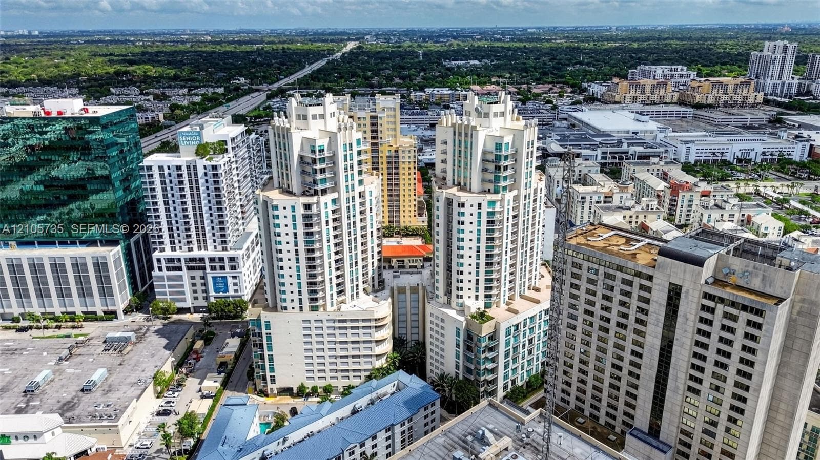 Aerial perspective of dual-tower high-rise residential architecture featuring glass-paneled balconies and a central podium structure