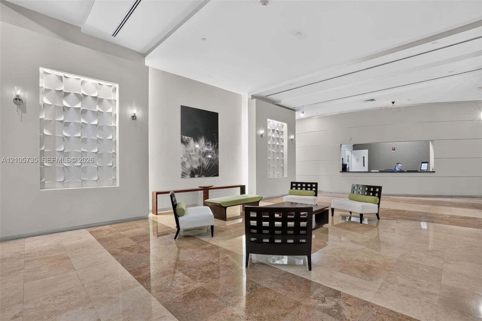Grand lobby featuring polished stone flooring, recessed architectural wall niches with textured dimensional tile, custom crown molding, and recessed ceiling lighting