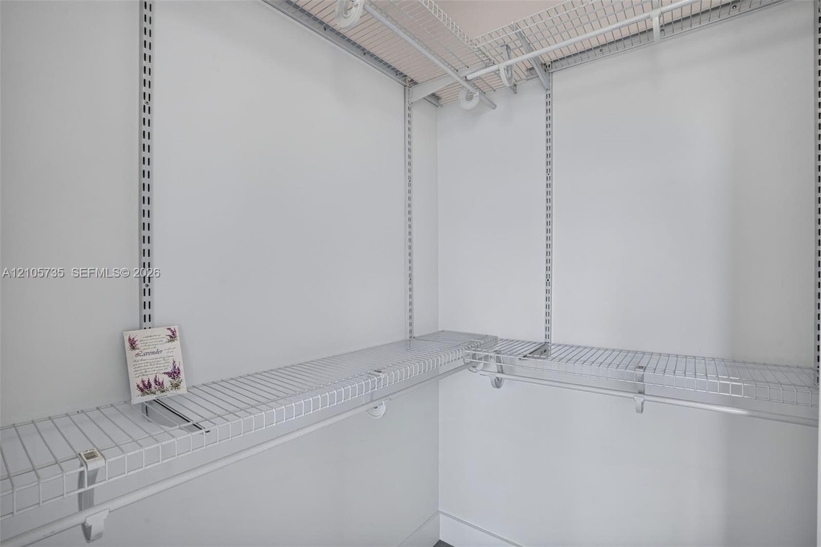 Walk-in storage space featuring adjustable metal shelving tracks and wire rack storage systems with integrated hanging rods