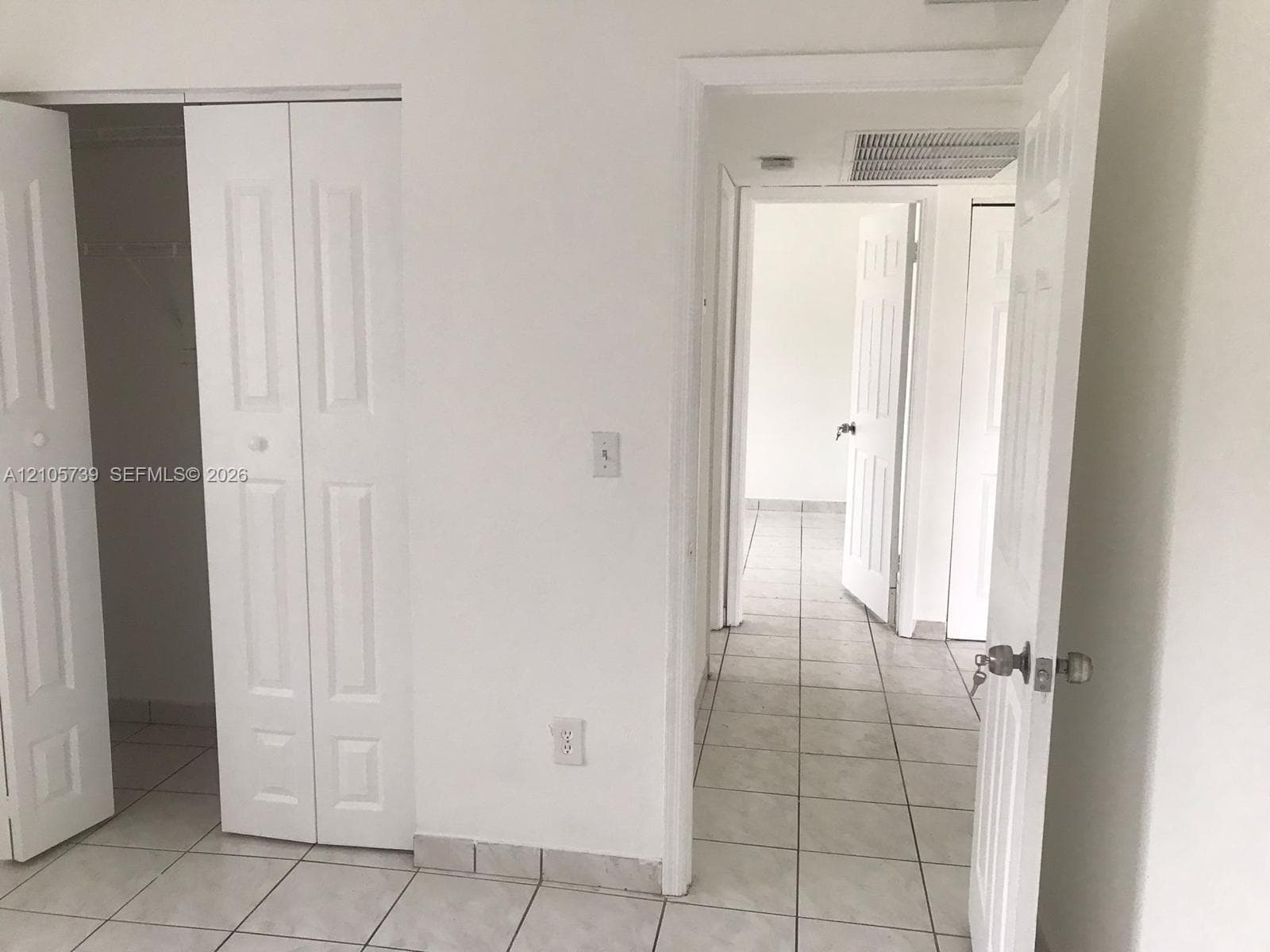 Interior space featuring light-colored tile flooring, white panel doors, and built-in closet storage