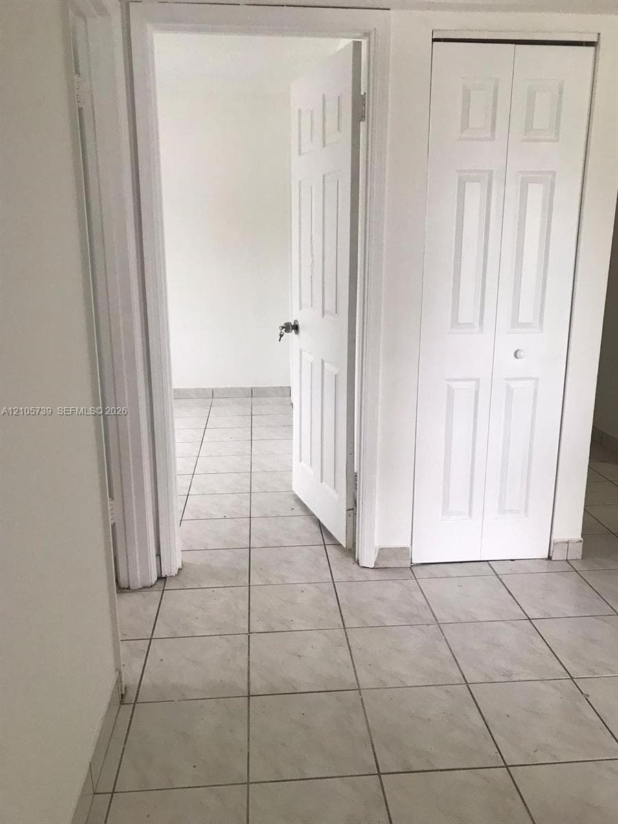 Ceramic tile flooring, six-panel interior swing door, and bifold closet door