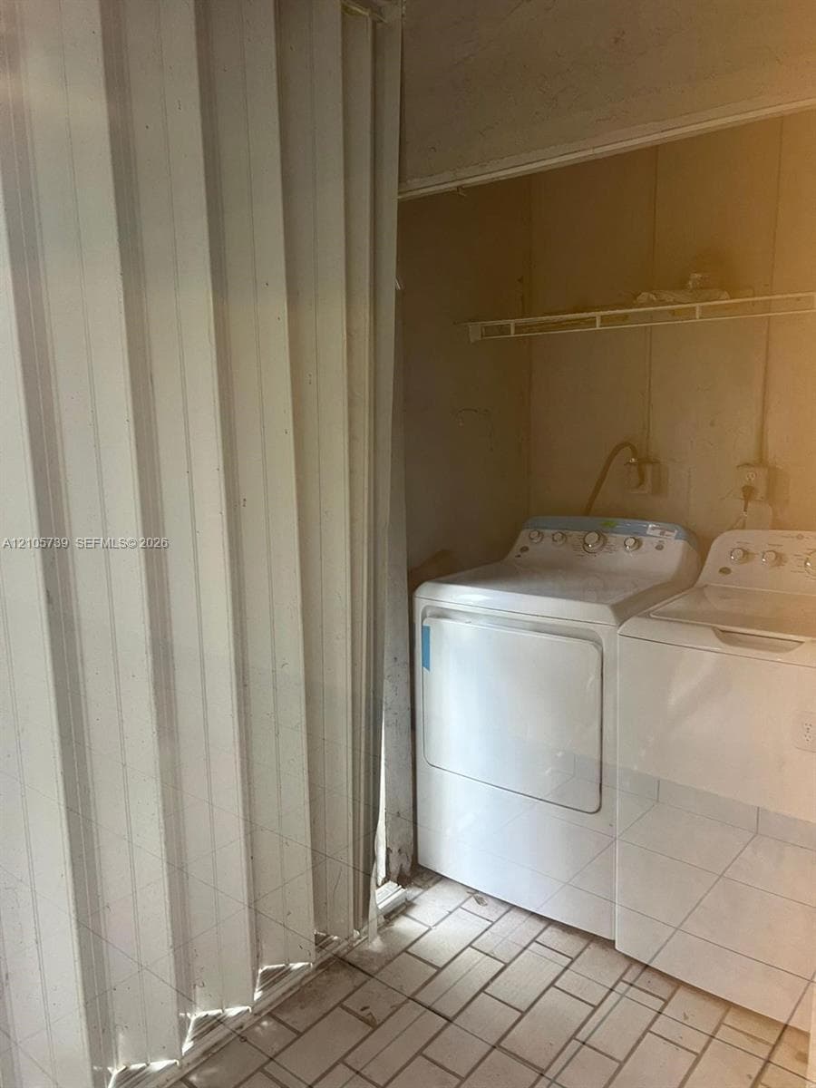 Laundry area featuring tile flooring, built-in shelving, and a vertical folding privacy door