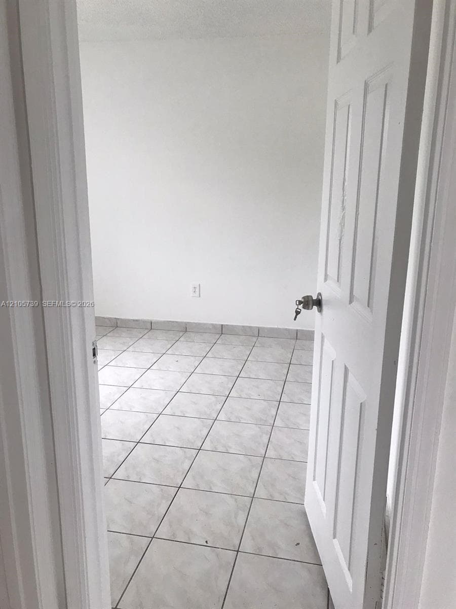 Interior space featuring neutral wall tones, large-format tile flooring, and a classic six-panel white door