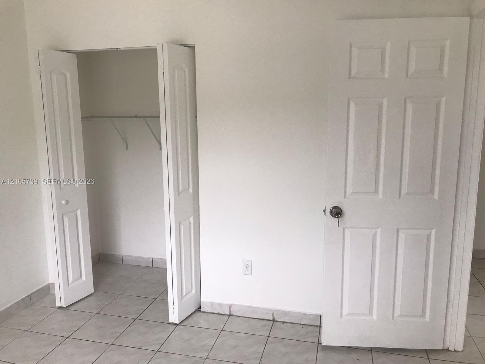 Interior room featuring neutral floor tiling, a walk-in closet with built-in shelving, and white six-panel doors