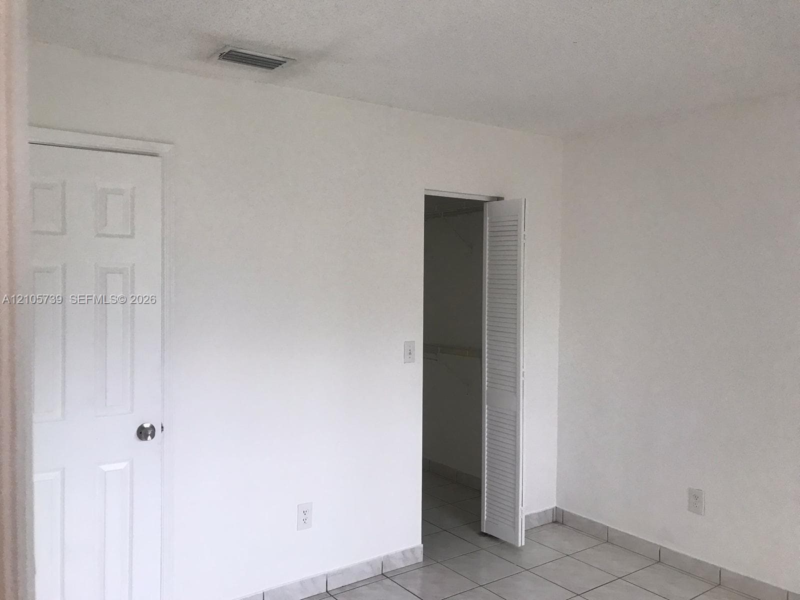 Interior space featuring ceramic tile flooring, a six-panel door, and a louvered closet door