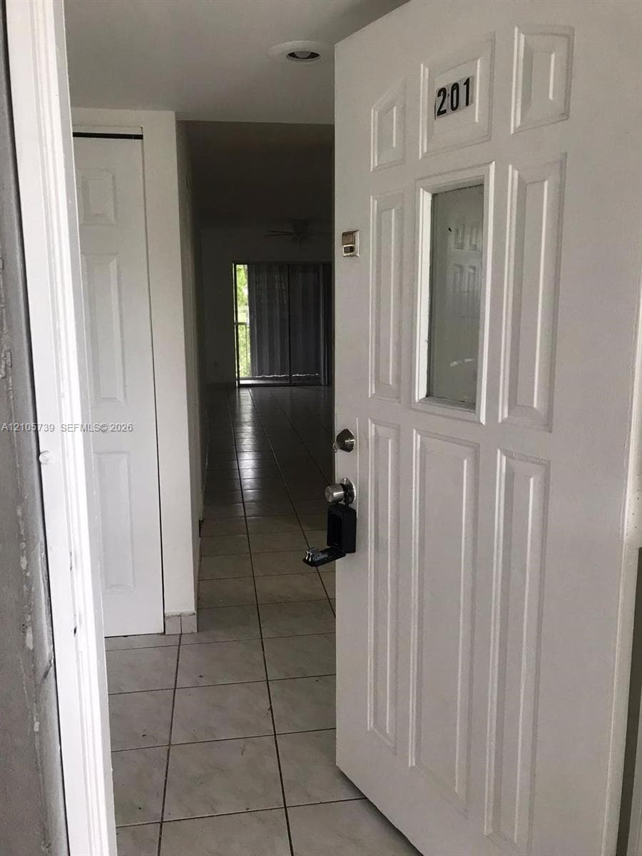 Entryway featuring a white paneled door with a glass insert, light-toned tiled flooring, and a two-panel closet door