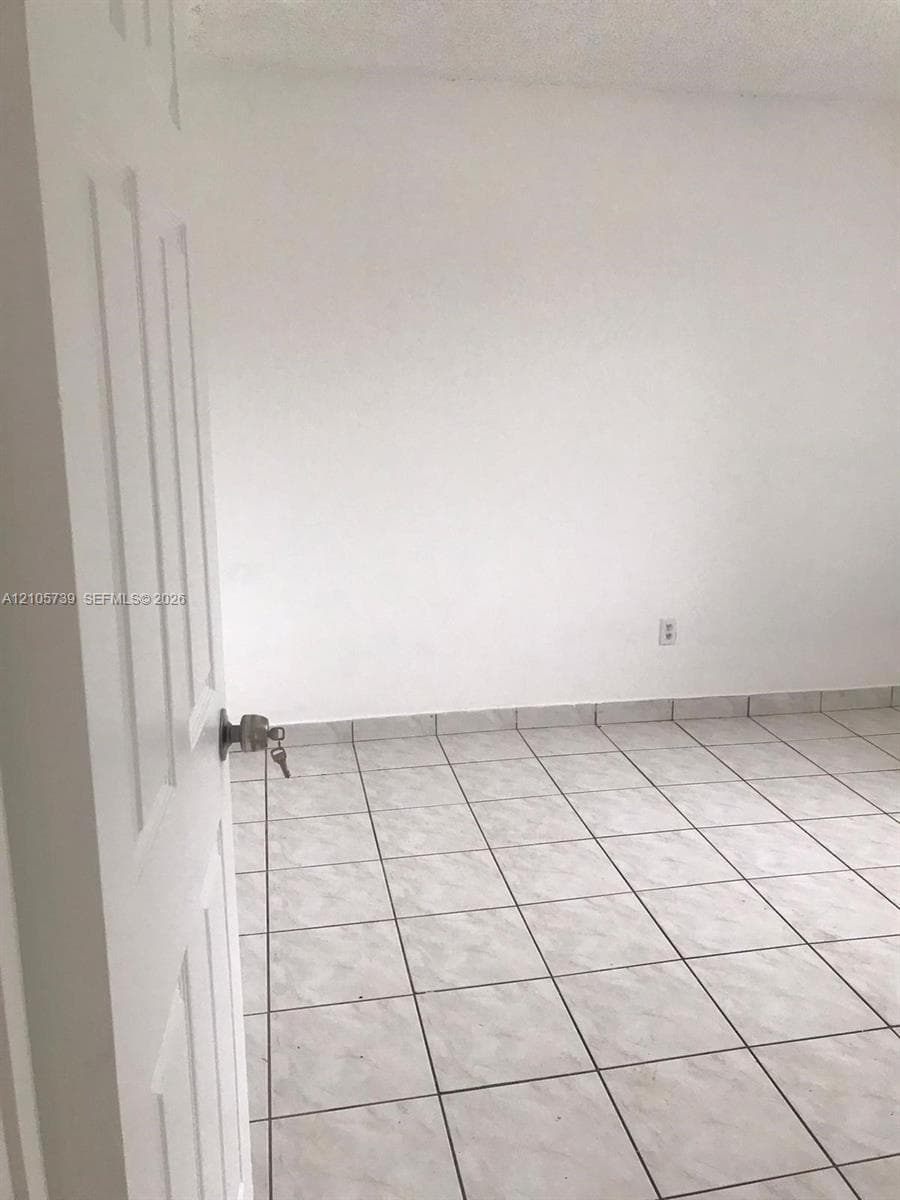 Interior space featuring white-painted walls and light-toned, square ceramic floor tiling