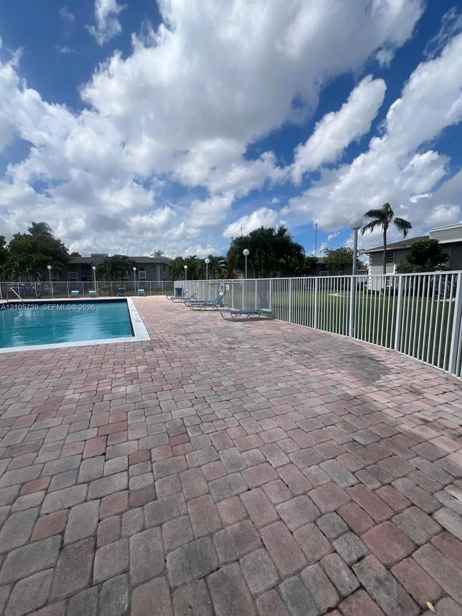 Swimming pool featuring a paver patio and metal perimeter fencing
