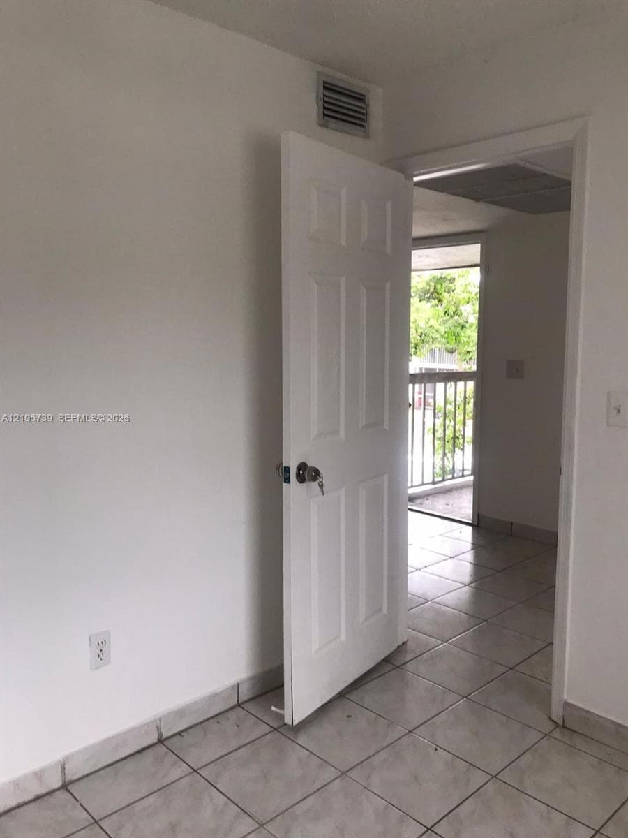 Interior space featuring light-toned ceramic tile flooring and a six-panel door with a keyed entry lock