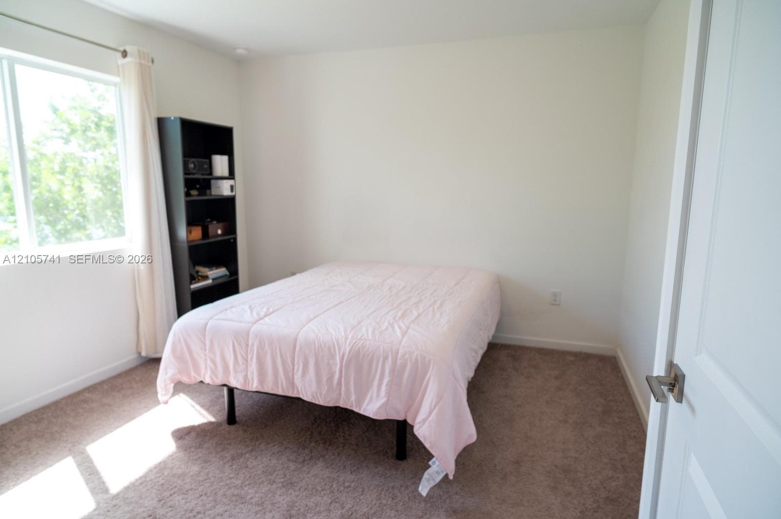 Neutral-toned room featuring wall-to-wall carpeting, crisp white walls, and a large window