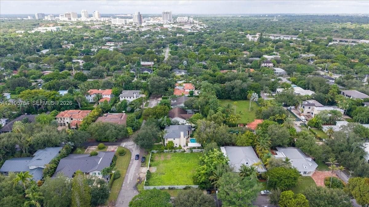 Aerial perspective of a corner lot situated in a tree-lined residential neighborhood with proximity to the urban skyline