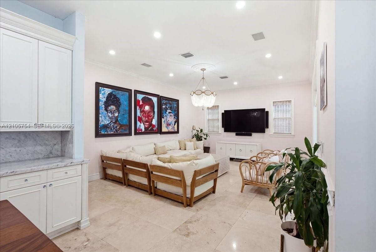 Living area featuring large-format tile flooring, recessed ceiling lighting, a decorative ceiling medallion, a multi-tiered crystal chandelier, and built-in white cabinetry with a stone countertop