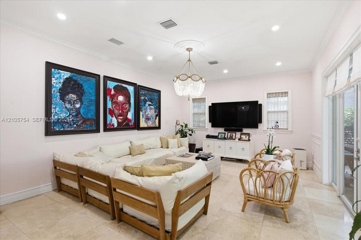 Living area featuring stone tile flooring, crown molding, a decorative ceiling medallion, an orb-style chandelier, and glass sliding doors