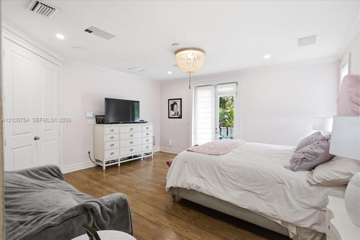 Room featuring wood-finish flooring, recessed lighting, crown molding, a decorative crystal-style chandelier, and a glass-paneled exterior door