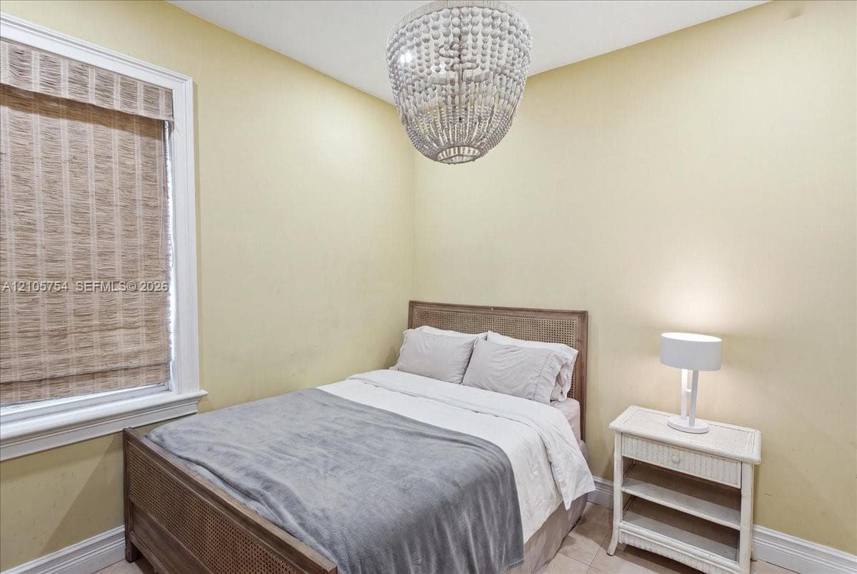 Beaded chandelier fixture, window with natural woven shade, and neutral wall paint