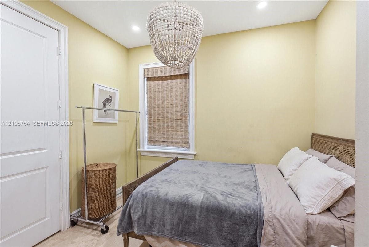 Textured bead chandelier, recessed ceiling lighting, and a window with a woven wood shade