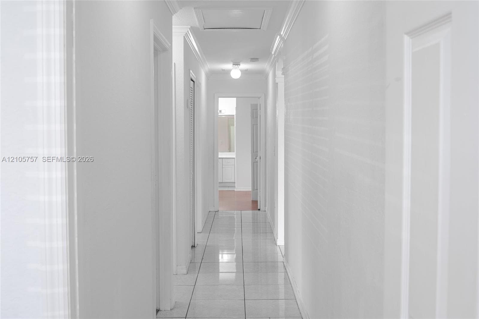 Hallway featuring ceramic tile flooring, crown molding, and ceiling-mounted light fixtures
