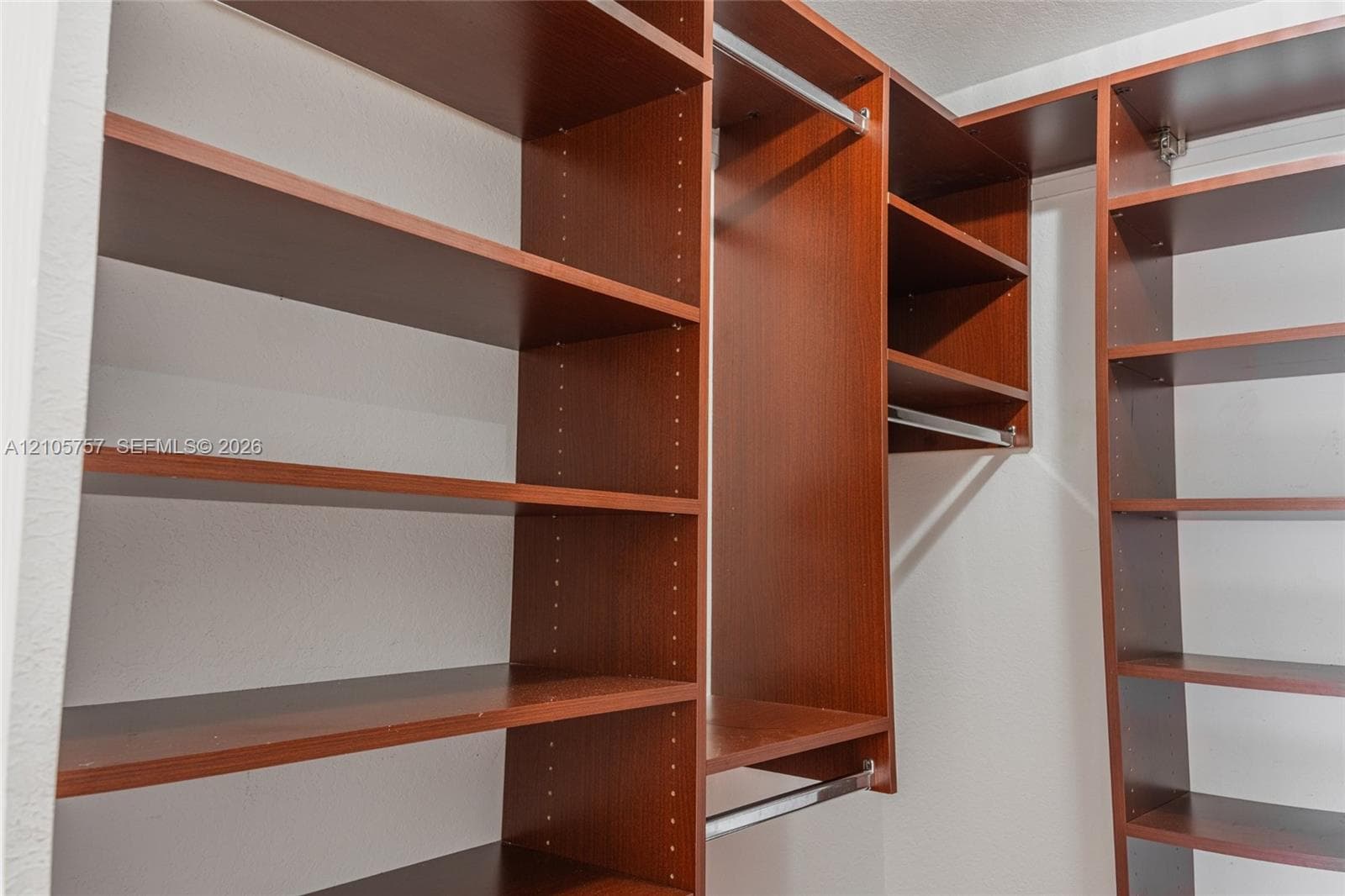 Custom wood-finish closet system featuring adjustable shelving units, integrated hanging rods, and corner storage configurations