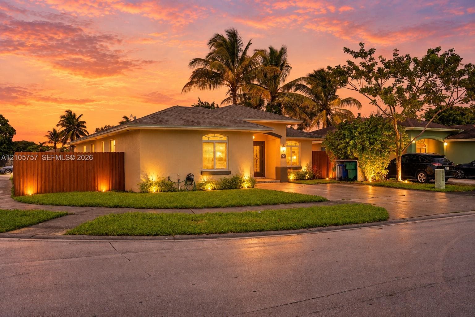 Single-story exterior with a stucco finish, arched window accents, wood-style privacy fencing, and a concrete driveway