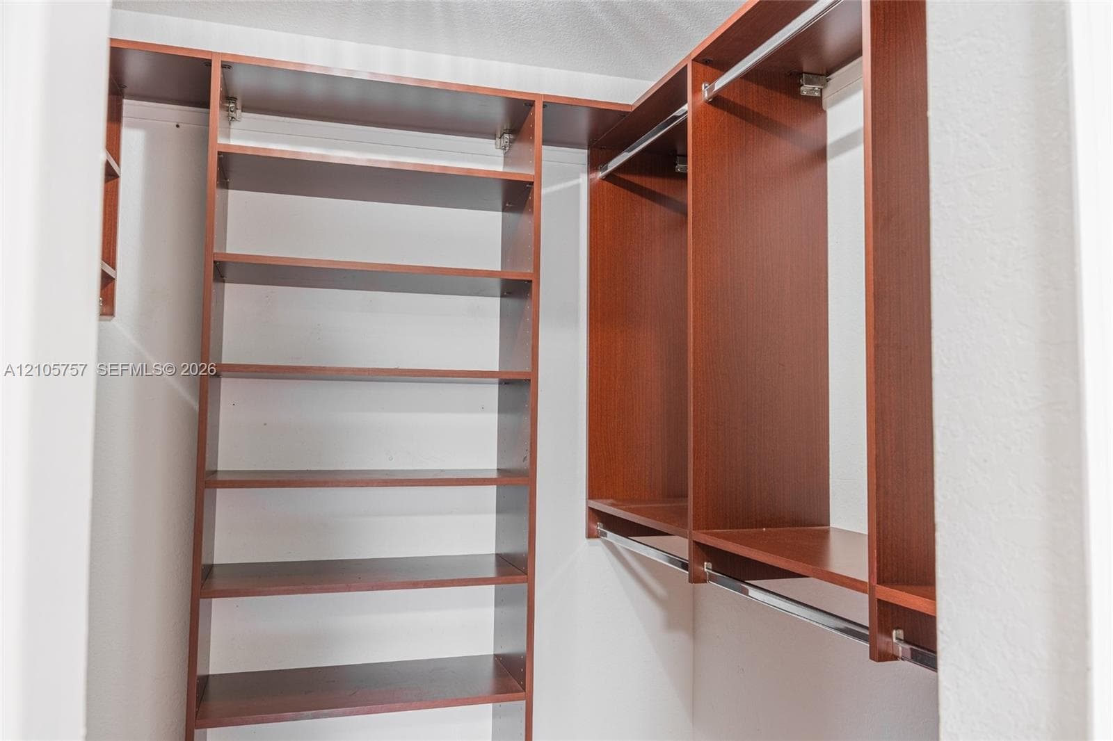 Walk-in closet featuring floor-to-ceiling wooden shelving units and dual-level metal hanging rods