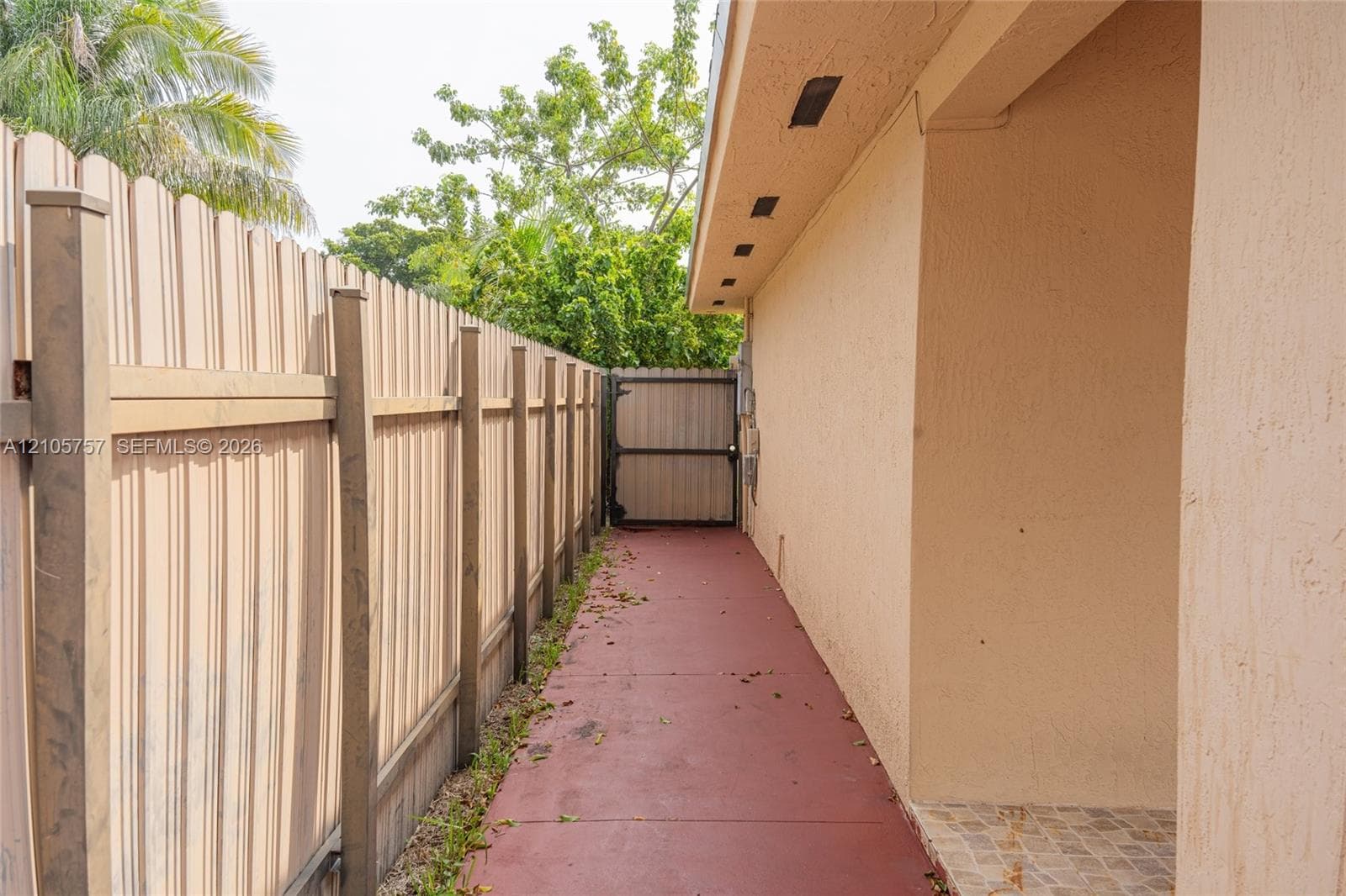 Stucco exterior side path featuring a full-height privacy fence and a secured gate