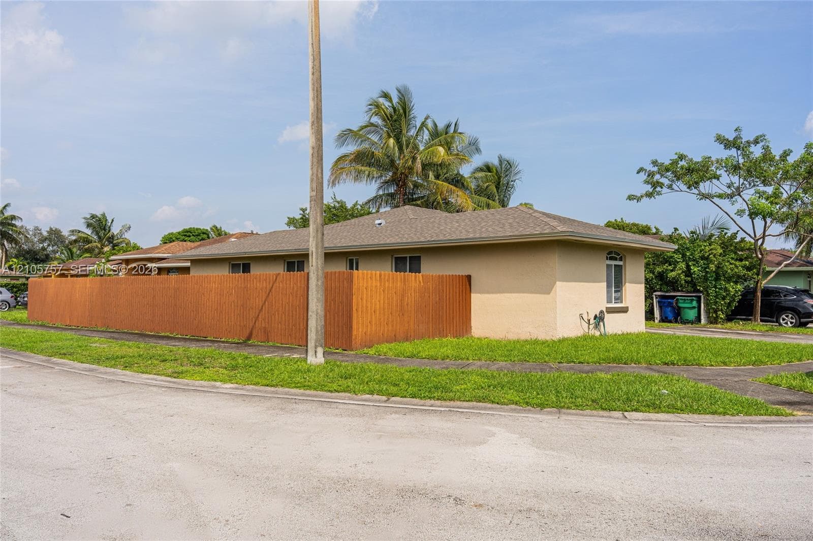 Stucco exterior featuring a wood-panel privacy fence and a hip roofline