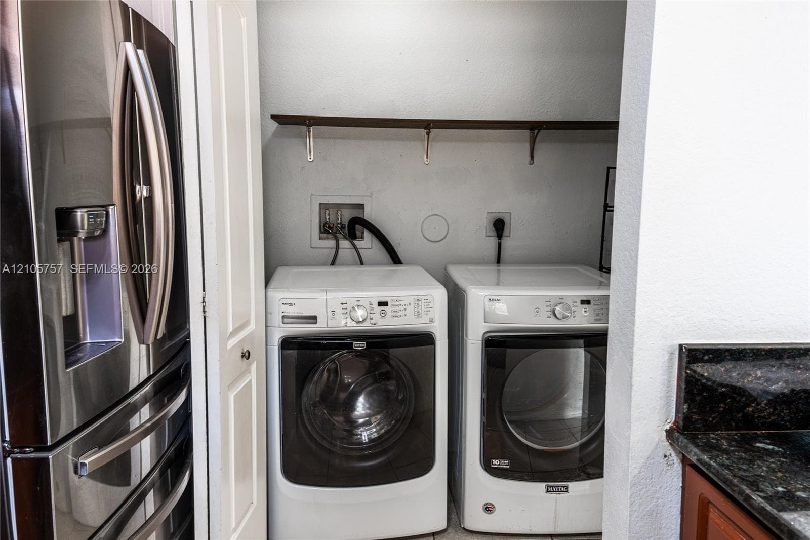 Laundry closet featuring built-in shelving, water hookups, and dedicated electrical outlets
